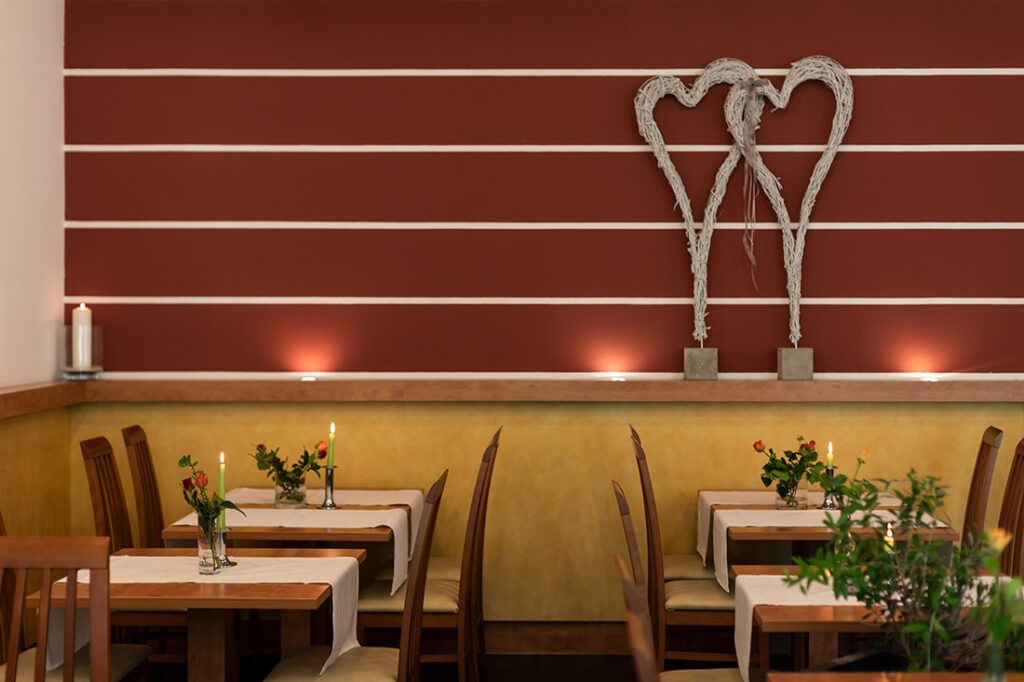 Die Tische im Restaurant Karlstadt sind eingedeckt mit weißen Tischläufern, Stabkerzen und Blumendekoration