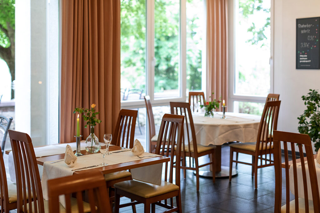 Blick in das Restaurant Karlstadt mit eingedeckten und dekorierten Holztischen an den Panoramafenstern